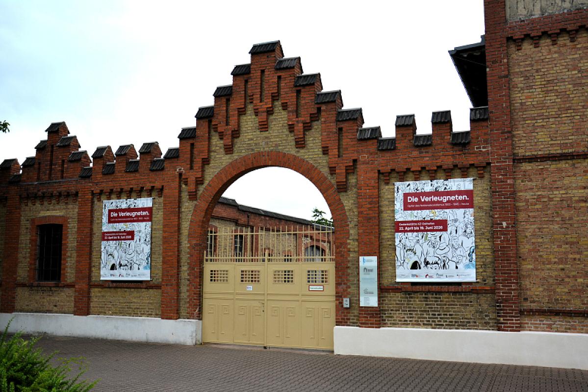 Osthofen, 2026, Entrance gate to the former camp featuring a poster for the travelling exhibition »The Disavowed«, Stiftung Denkmal